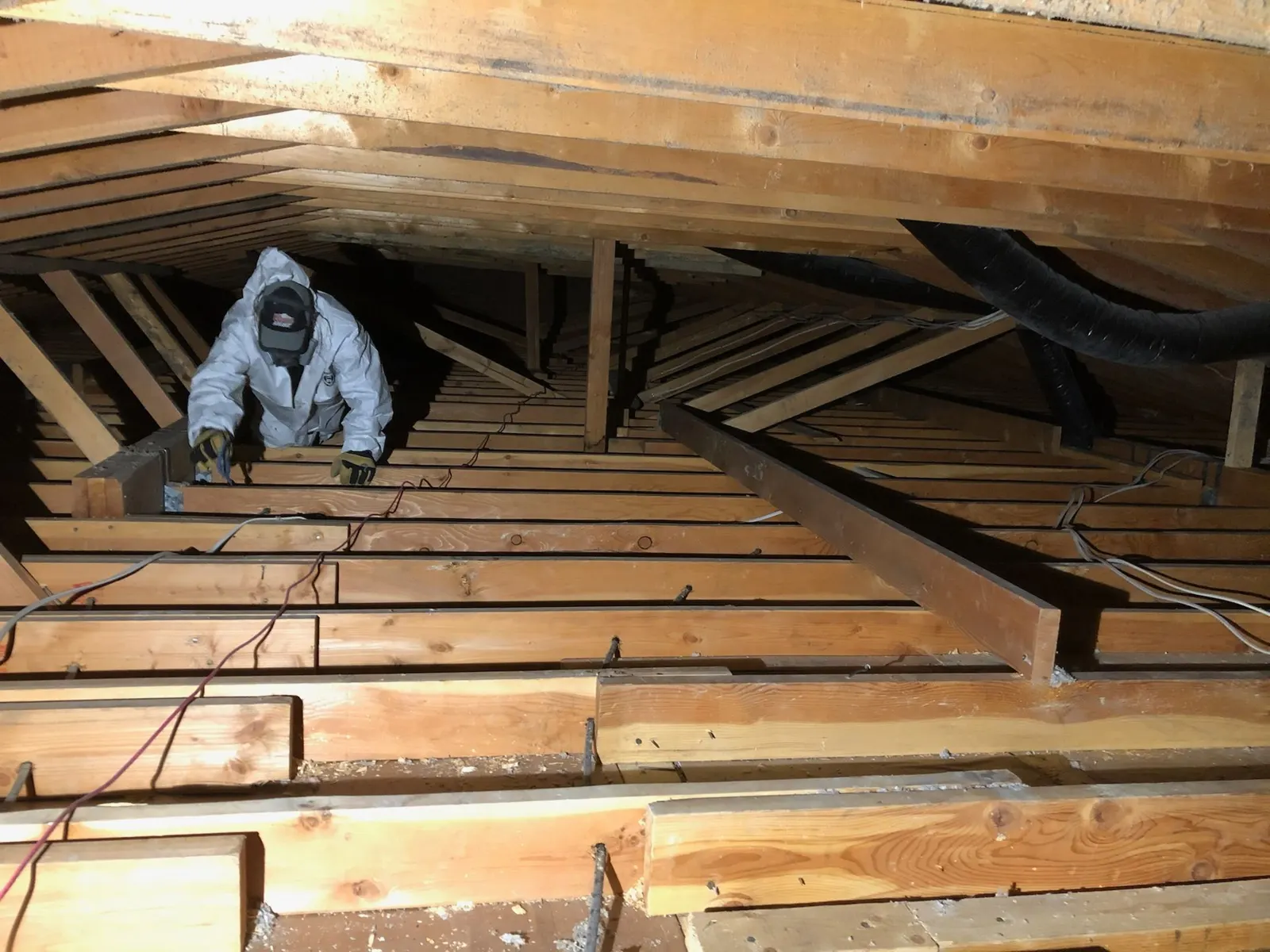 Installer moving between attic trusses to inspect and prepare the ceiling plane