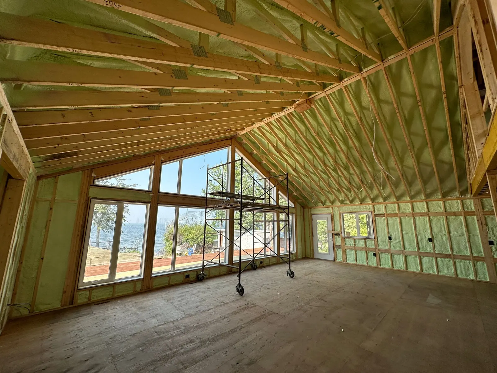 New home great room with green closed cell spray foam on the walls and vaulted ceiling