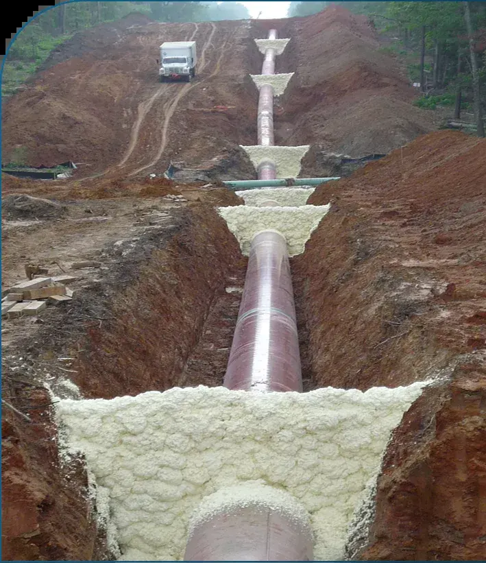 Spray foam trench breakers around a pipeline in an open trench