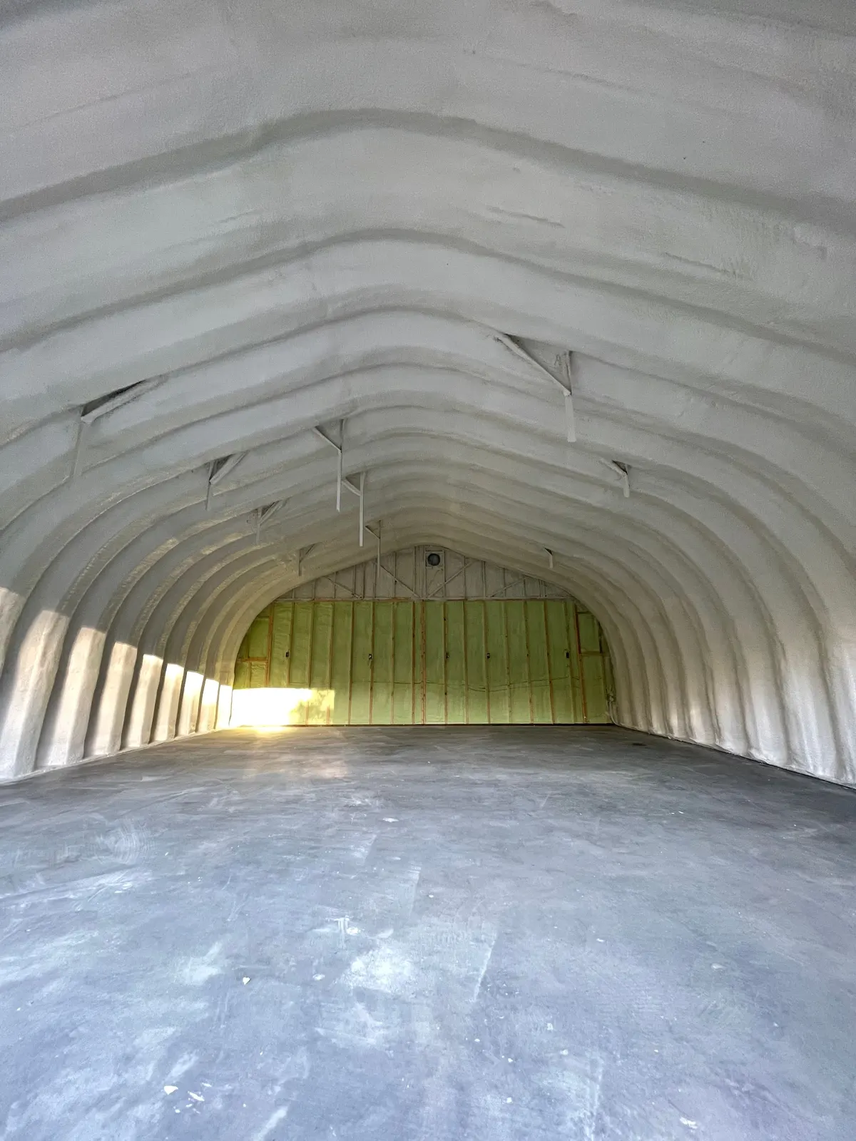 Quonset shop interior with spray foam on the curved steel walls