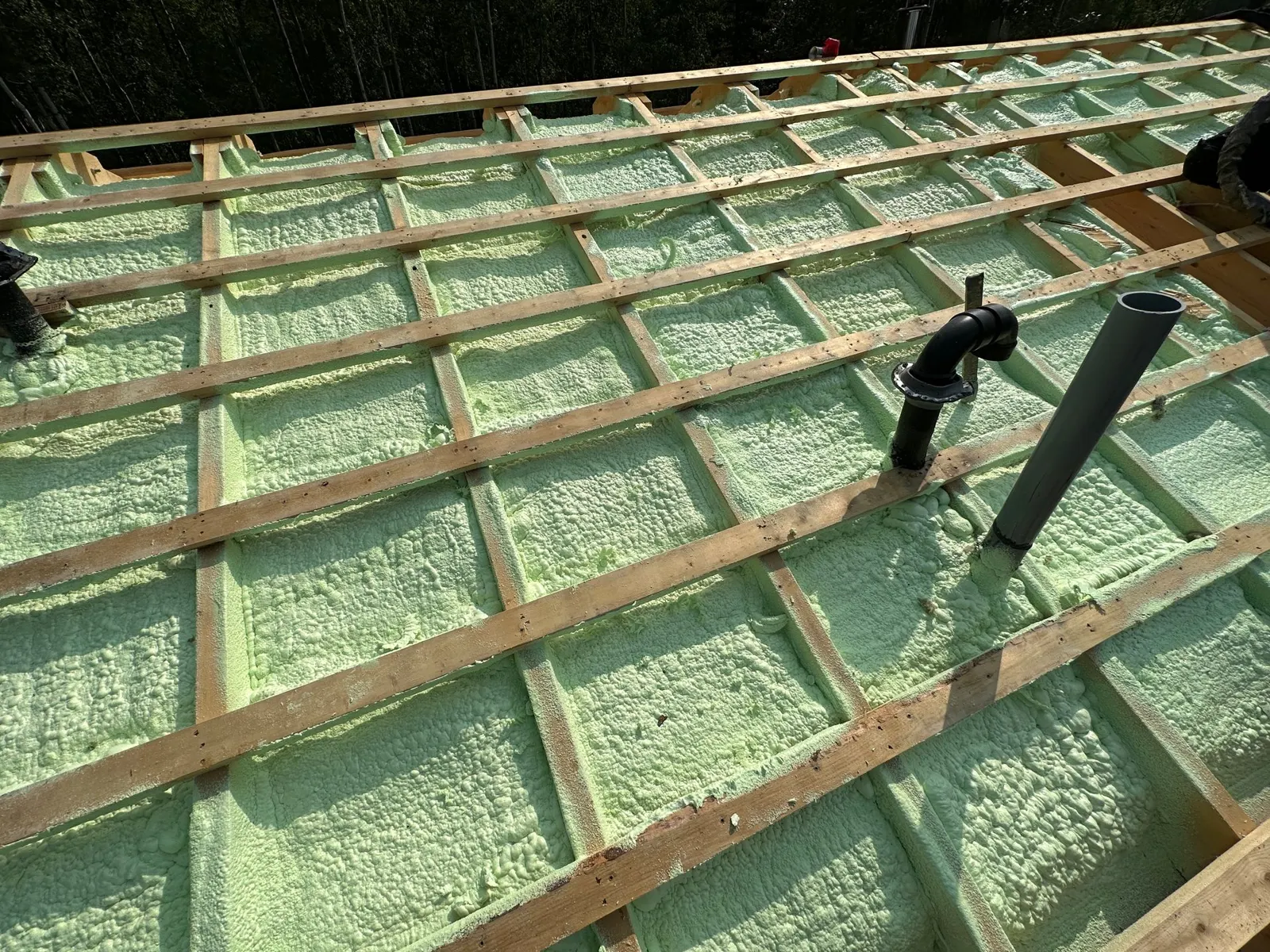 Underside of a roof deck sprayed with closed cell foam between the rafters